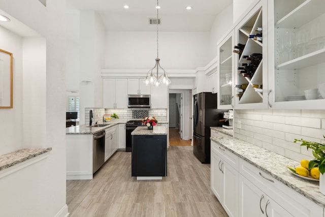 569 Dove Creek Cir, Grapevine, TX 76051 - kitchen with black appliances, a sink, a center island, backsplash, and white cabinetry