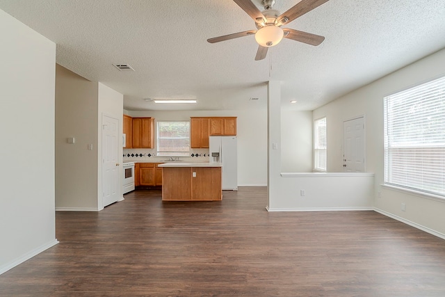4617 Barnhill Ln, Fort Worth, TX 76135 - kitchen with white appliances, a kitchen island, dark wood-style floors, light countertops, and a textured ceiling