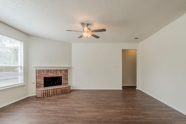 4617 Barnhill Ln, Fort Worth, TX 76135 - unfurnished living room featuring dark wood-style flooring, a ceiling fan, a brick fireplace, a textured ceiling, and baseboards