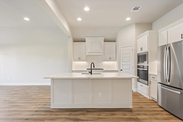 514 Geyser Trl, Waco, TX 76657 - kitchen with stainless steel appliances, custom exhaust hood, a sink, an island with sink, and light countertops