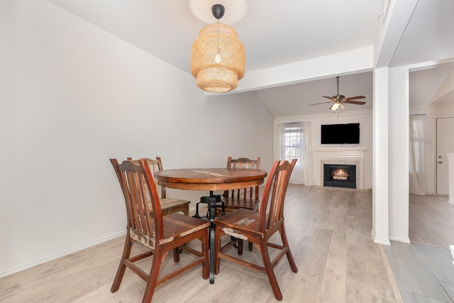 8750 Park Ln Unit 151, Dallas, TX 75231 - dining space with a ceiling fan, light wood-type flooring, a lit fireplace, and baseboards