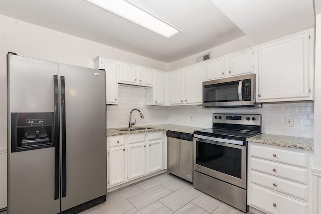8750 Park Ln Unit 151, Dallas, TX 75231 - kitchen featuring appliances with stainless steel finishes, a sink, decorative backsplash, and white cabinetry