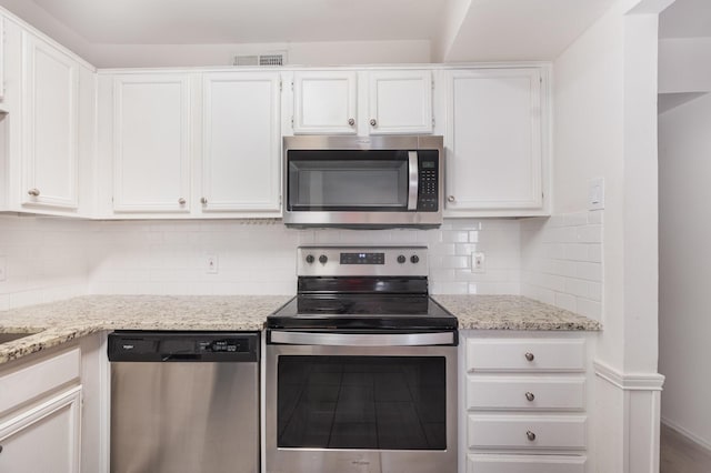 8750 Park Ln Unit 151, Dallas, TX 75231 - kitchen featuring stainless steel appliances, white cabinetry, tasteful backsplash, and light stone countertops