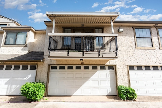 8750 Park Ln Unit 151, Dallas, TX 75231 - rear view of house with a balcony, stucco siding, and a garage