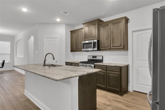 2917 Bobcat Dr, Melissa, TX 75454 - kitchen featuring stainless steel appliances, a sink, tasteful backsplash, a center island with sink, and light wood-style flooring