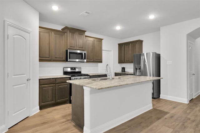 2917 Bobcat Dr, Melissa, TX 75454 - kitchen with appliances with stainless steel finishes, a sink, light wood finished floors, a center island with sink, and recessed lighting