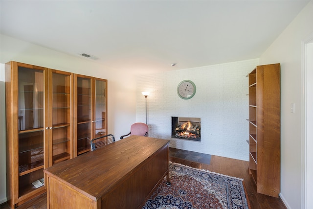 office space with a multi sided fireplace and dark wood-style flooring