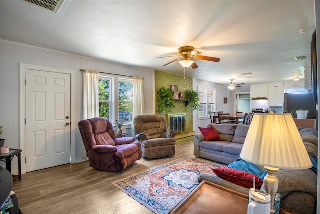 13591 County Road 420, Tyler, TX 75704 - living area featuring healthy amount of natural light, a ceiling fan, wood finished floors, a brick fireplace, and ornamental molding