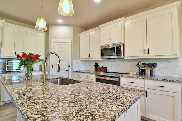 130 County Road 2630, Decatur, TX 76234 - kitchen featuring stainless steel appliances, a sink, a center island with sink, light stone counters, and white cabinetry