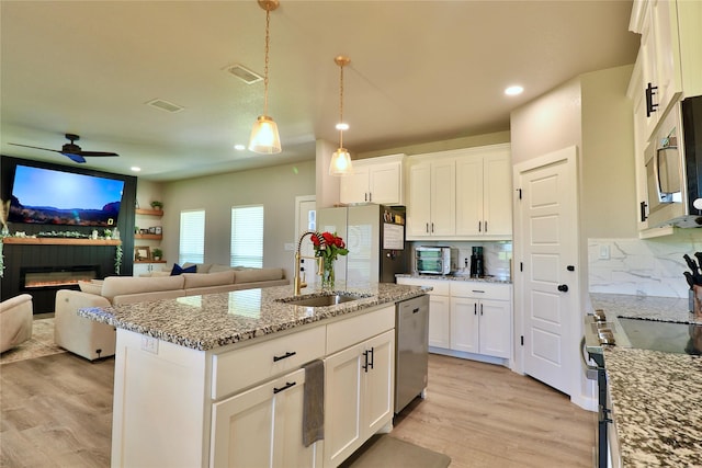 130 County Road 2630, Decatur, TX 76234 - kitchen featuring appliances with stainless steel finishes, a sink, open floor plan, light wood-type flooring, and white cabinetry