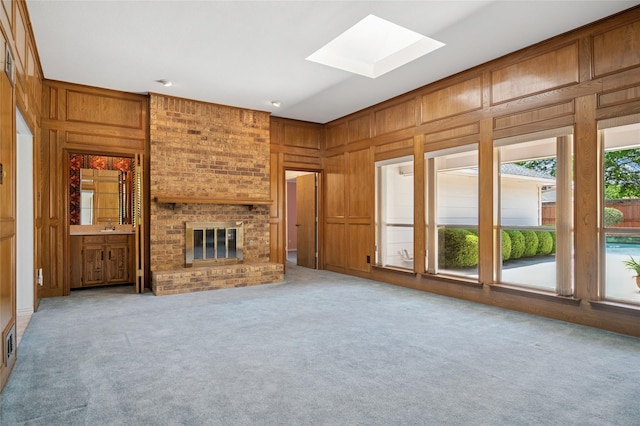 1706 Morningstar Trl, Richardson, TX 75081 - unfurnished living room featuring a skylight, carpet flooring, wooden walls, a fireplace, and a sink