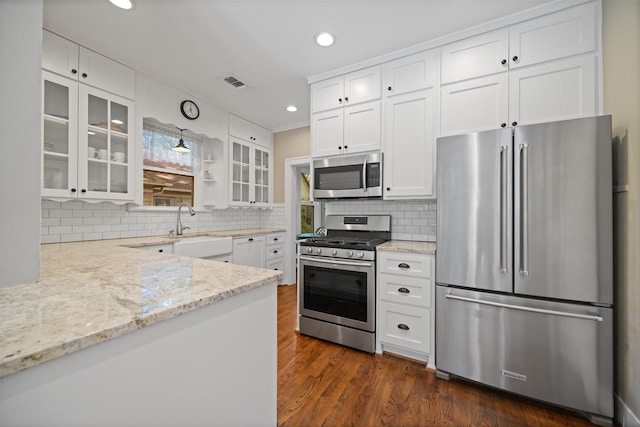 1143 N Winnetka Ave, Dallas, TX 75208 - kitchen featuring appliances with stainless steel finishes, a sink, dark wood-type flooring, light stone countertops, and glass insert cabinets