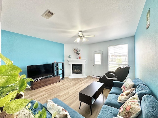 6468 Payton Dr, Fort Worth, TX 76131 - living room featuring ceiling fan, light wood-style floors, a fireplace with raised hearth, and baseboards