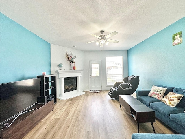 6468 Payton Dr, Fort Worth, TX 76131 - living area featuring wood finished floors, a glass covered fireplace, ceiling fan, and a textured ceiling