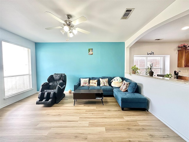 6468 Payton Dr, Fort Worth, TX 76131 - living room featuring arched walkways, light wood finished floors, ceiling fan, and baseboards