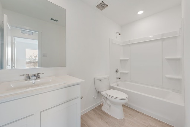 bathroom featuring wood finished floors, toilet, vanity, shower / tub combination, and baseboards