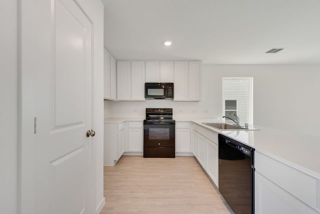 kitchen with black appliances, a sink, light wood-type flooring, recessed lighting, and white cabinetry