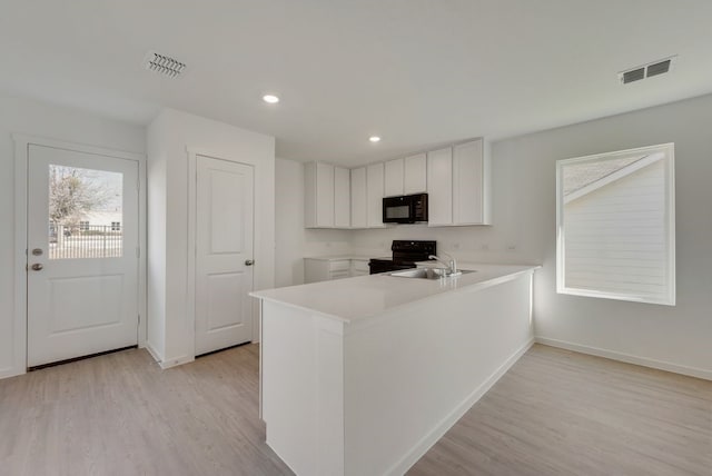 kitchen featuring black appliances, a peninsula, light wood-style floors, baseboards, and recessed lighting