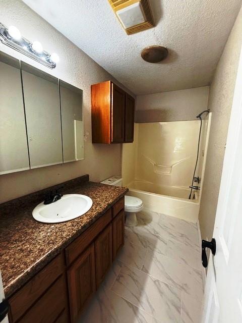 426 Gun Club Rd, Denison, TX 75021 - bathroom with a textured ceiling,  shower combination, toilet, marble look tiles, and vanity