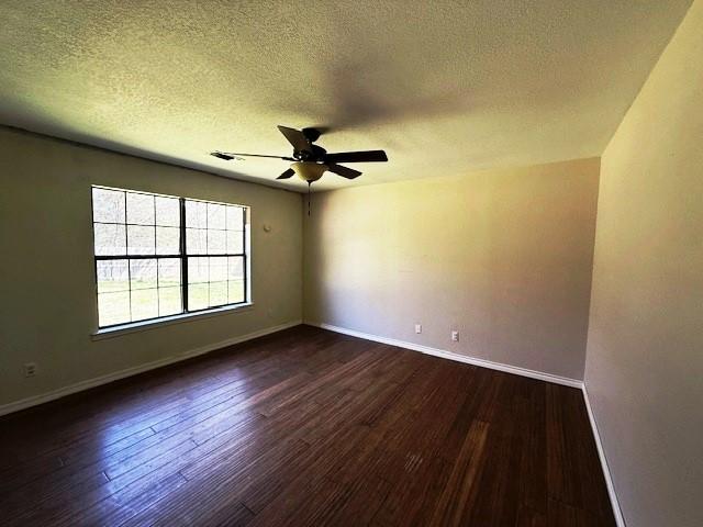 426 Gun Club Rd, Denison, TX 75021 - empty room with ceiling fan, dark wood finished floors, a textured ceiling, and baseboards