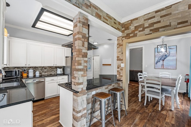 4013 Wisteria Ln, Benton, LA 71006 - kitchen with appliances with stainless steel finishes, ornate columns, crown molding, dark countertops, and dark wood-style floors