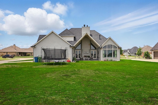 1316 Sparrow Hawk Ln, Gunter, TX 75058 - rear view of property with a trampoline, a yard, a chimney, and stucco siding