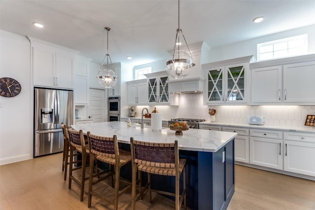2228 Sandrellan St, Fort Worth, TX 76008 - kitchen featuring stainless steel appliances, tasteful backsplash, a center island with sink, a breakfast bar, and light stone countertops