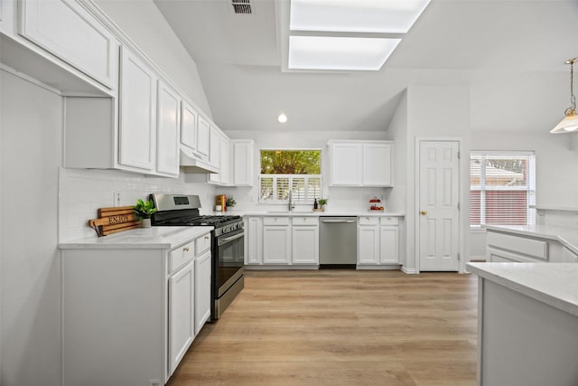 2402 Greenfield Cir, Garland, TX 75040 - kitchen with stainless steel appliances, white cabinets, decorative backsplash, lofted ceiling, and under cabinet range hood