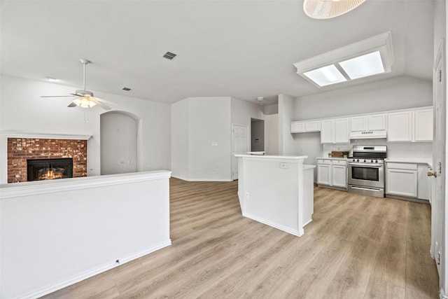 2402 Greenfield Cir, Garland, TX 75040 - kitchen with stainless steel range with electric cooktop, open floor plan, a fireplace, under cabinet range hood, and light wood-type flooring