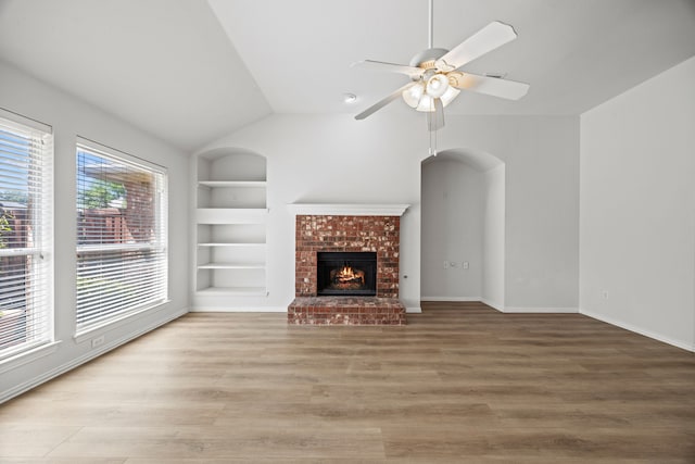 2402 Greenfield Cir, Garland, TX 75040 - unfurnished living room with built in shelves, lofted ceiling, wood finished floors, a fireplace, and ceiling fan