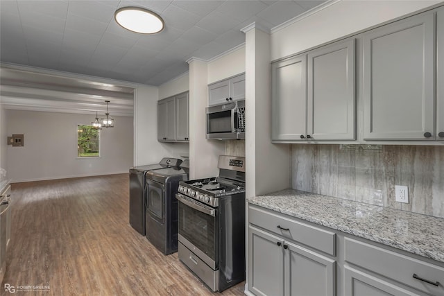 kitchen with appliances with stainless steel finishes, gray cabinetry, crown molding, washer and clothes dryer, and light wood finished floors