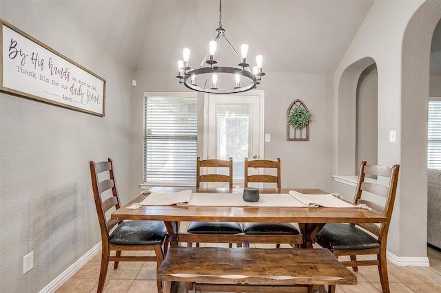 dining area with arched walkways, lofted ceiling, a chandelier, light tile patterned floors, and baseboards