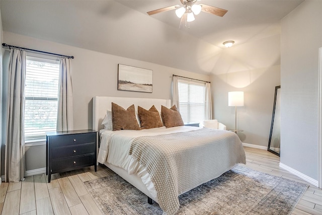bedroom featuring light wood finished floors, baseboards, and multiple windows
