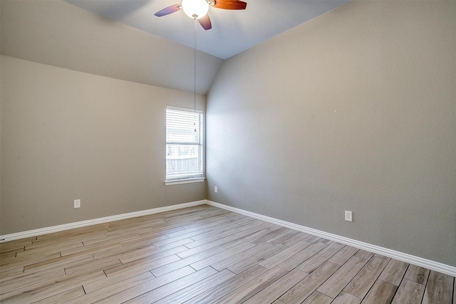 spare room with a ceiling fan, light wood-type flooring, baseboards, and lofted ceiling
