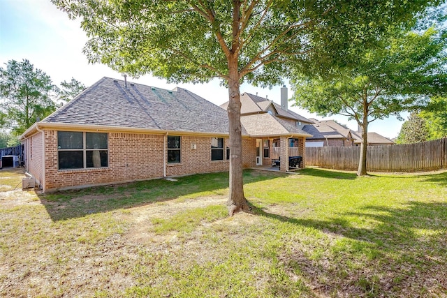 rear view of house with brick siding, a shingled roof, a chimney, and a patio