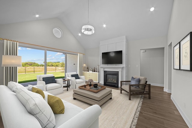 11549 Wulstone Rd, Fort Worth, TX 76052 - living room with high vaulted ceiling, wood finished floors, baseboards, a fireplace with flush hearth, and a chandelier