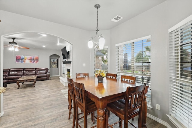 2210 Ridgewood Dr, Bridgeport, TX 76426 - dining space featuring arched walkways, light wood finished floors, ceiling fan, a large fireplace, and baseboards