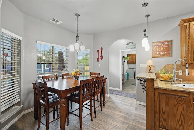 2210 Ridgewood Dr, Bridgeport, TX 76426 - dining room featuring light wood finished floors, arched walkways, washer / clothes dryer, baseboards, and a chandelier