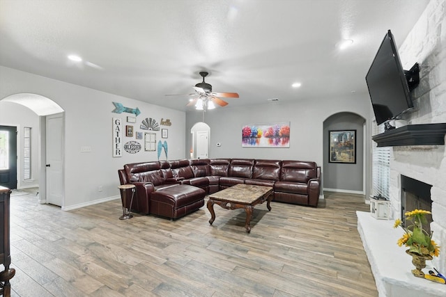 2210 Ridgewood Dr, Bridgeport, TX 76426 - living area with arched walkways, a ceiling fan, light wood-style flooring, a large fireplace, and recessed lighting