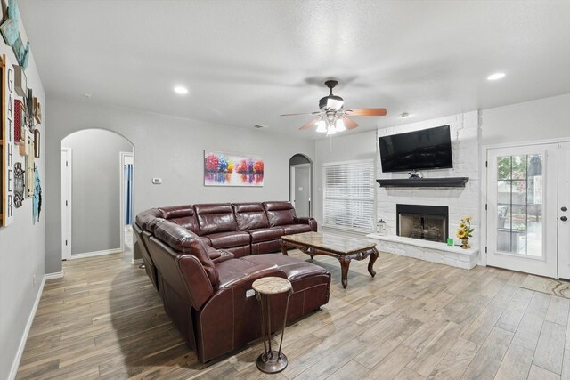 2210 Ridgewood Dr, Bridgeport, TX 76426 - living room featuring arched walkways, a ceiling fan, wood finished floors, a stone fireplace, and recessed lighting