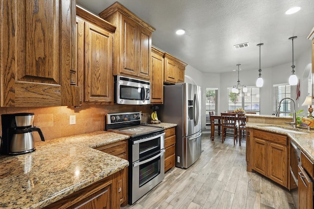 2210 Ridgewood Dr, Bridgeport, TX 76426 - kitchen with appliances with stainless steel finishes, a sink, brown cabinetry, decorative backsplash, and light stone counters