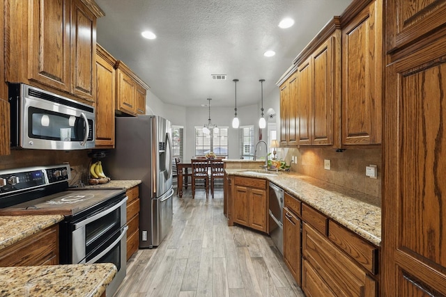 2210 Ridgewood Dr, Bridgeport, TX 76426 - kitchen with appliances with stainless steel finishes, a sink, a peninsula, light wood finished floors, and brown cabinets