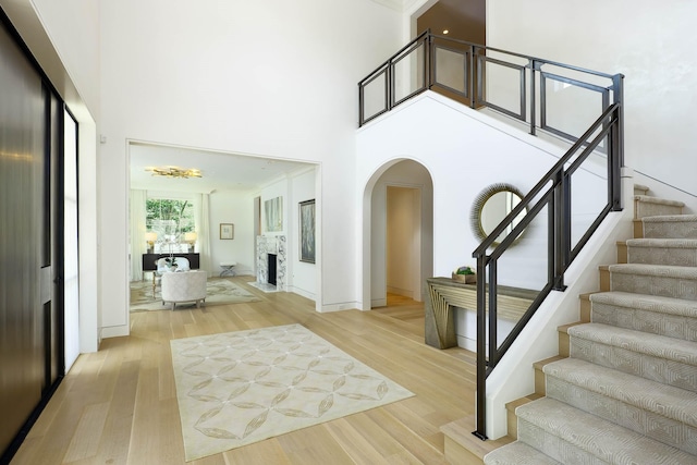 3906 Shenandoah St, Highland Park, TX 75205 - foyer featuring arched walkways, a towering ceiling, stairway, light wood-style flooring, and a chandelier