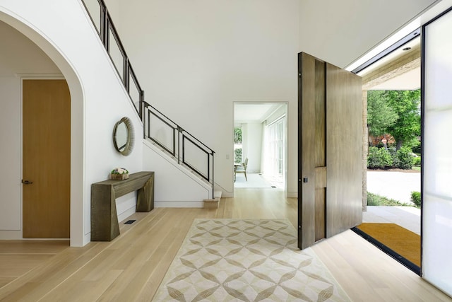 3906 Shenandoah St, Highland Park, TX 75205 - foyer entrance featuring arched walkways, light wood finished floors, a towering ceiling, and stairs