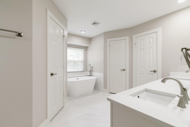 7300 Frances Ct, North Richland Hills, TX 76182 - bathroom featuring marble look tiles, a freestanding bath, double vanity, and recessed lighting