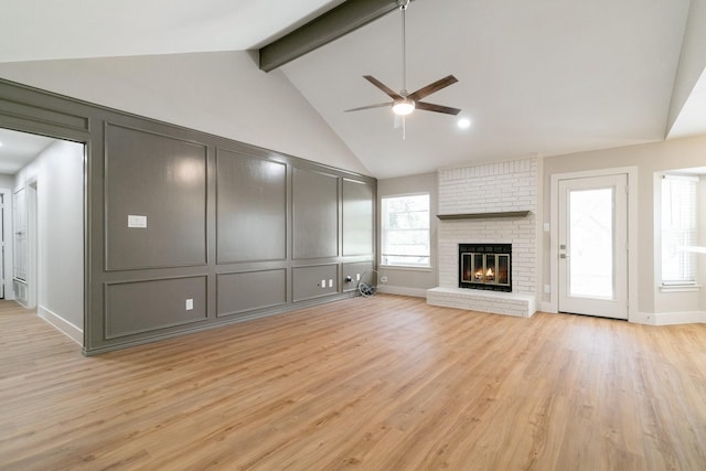 7300 Frances Ct, North Richland Hills, TX 76182 - unfurnished living room featuring ceiling fan, a decorative wall, beam ceiling, light wood-style floors, and a brick fireplace