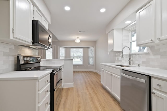 7300 Frances Ct, North Richland Hills, TX 76182 - kitchen featuring stainless steel appliances, a sink, light wood-style flooring, white cabinetry, and baseboards