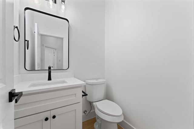 2915 NW Loraine St, Fort Worth, TX 76106 - bathroom with toilet, vanity, baseboards, and wood finished floors