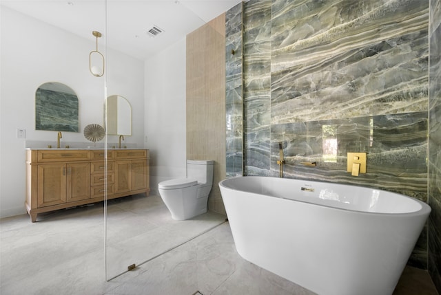 2535 Exline St, Dallas, TX 75215 - bathroom with marble tiled flooring, tile walls, a freestanding bath, double vanity, and toilet
