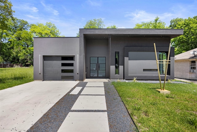 2535 Exline St, Dallas, TX 75215 - contemporary home featuring concrete driveway, an attached garage, stucco siding, and a front lawn